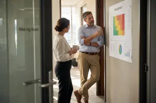 Manager observes technician checking ergonomic station in a calm, sunlit office